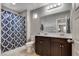 Charming bathroom featuring a double sink vanity, decorative mirror, and tiled shower with patterned curtain at 7559 Chimney Point Ct, Las Vegas, NV 89166
