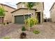 View of the front of a well-manicured home with a two-car garage, young trees and easy to maintain gravel landscaping at 7721 Sheliak St, North Las Vegas, NV 89084
