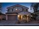 Exterior dusk shot of a two-story home showcasing landscape, tile roof, shutters, and two-car garage at 7878 Brianna Cheerful Ave, Las Vegas, NV 89178
