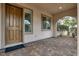 Inviting covered patio with brick flooring, featuring a wooden door, large windows, and desert landscaping at 7878 Brianna Cheerful Ave, Las Vegas, NV 89178