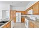 Kitchen featuring wood cabinets, granite countertops, and modern white appliances, designed for culinary convenience at 7990 Timber Horn Ct, Las Vegas, NV 89147