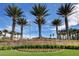 Community entrance featuring 'Spanish Trail' sign surrounded by lush palm trees and vibrant landscaping at 8051 Castle Pines Ave, Las Vegas, NV 89113
