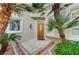 Welcoming front entrance with tiled steps, a wood door, and decorative glass details amidst manicured landscaping and mature trees at 8051 Castle Pines Ave, Las Vegas, NV 89113