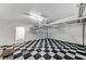 Spacious garage with checkerboard floors, overhead storage racks, and access door to interior at 8051 Castle Pines Ave, Las Vegas, NV 89113