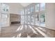 Bright living room with soaring ceilings, a modern fireplace, wood flooring, and a wall of windows overlooking the backyard at 8051 Castle Pines Ave, Las Vegas, NV 89113