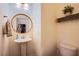 Cozy half-bathroom with a pedestal sink, round mirror, and wood-look tile flooring at 8171 California Pine St, Las Vegas, NV 89166