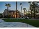 Expansive backyard with artificial turf, palm trees, and a glimpse of outdoor furniture and a pool at 9012 Alpine Peaks Ave, Las Vegas, NV 89147