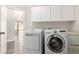 Bright laundry area with overhead cabinets, new washer and dryer, and view to the sunroom beyond at 9604 Windom Point Ave, Las Vegas, NV 89129