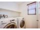 Convenient laundry area with modern washer and dryer, shelving, and window at 961 Wembly Hills Pl, Henderson, NV 89011