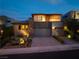 Contemporary home exterior featuring professional landscape, three-car garage and architectural lighting at twilight at 10313 Jade Point Dr, Las Vegas, NV 89135