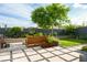 Landscaped backyard featuring a stone patio, wooden bench, green lawn, privacy wall, and mature shade tree at 11813 Pippa Ave, Las Vegas, NV 89138