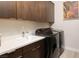 Modern laundry room boasts dark cabinetry, white countertops, and black washer and dryer set at 11813 Pippa Ave, Las Vegas, NV 89138