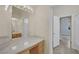 Bathroom featuring a long vanity, quartz countertops, and a large framed mirror with a view into the arched doorway at 1324 European Dr, Henderson, NV 89052