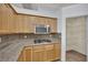 The kitchen boasts wood cabinets, granite countertops, tile backsplash, and stainless steel microwave and gas cooktop at 1324 European Dr, Henderson, NV 89052