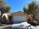 Tan single-story home with a two-car garage, desert landscaping and a clear blue sky at 3029 Frigate Way, North Las Vegas, NV 89084