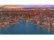 Stunning dusk aerial of a waterfront community showcasing canal homes and a vibrant city skyline in the distance at 3080 Yankee Clipper Dr, Las Vegas, NV 89117