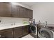 Well-appointed laundry room with dark cabinets, a large countertop, modern washer and dryer, and ample storage space at 4024 Desert Trace Ct, Las Vegas, NV 89129
