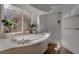 Sunlit bathroom featuring a modern tub, a separate glass-enclosed shower, and a view of the outdoor greenery at 4594 Blue Mesa Way, Las Vegas, NV 89129