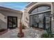 The entrance showcases an ornate glass double-door with transom, framed by a tiled courtyard and lush landscaping at 4594 Blue Mesa Way, Las Vegas, NV 89129