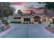 Desert home showcases a circular driveway and lush xeriscaping, complete with a private gate and a scenic desert sunset at 4594 Blue Mesa Way, Las Vegas, NV 89129