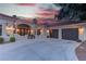 This desert home features a three-car garage, gated entrance, and manicured landscaping, complemented by a picturesque sunset sky at 4594 Blue Mesa Way, Las Vegas, NV 89129
