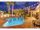 Backyard pool at night with palm trees, landscaping, and exterior lights at 4594 Blue Mesa Way, Las Vegas, NV 89129