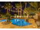 Inviting backyard pool surrounded by lush palms and ambient string lights at 4594 Blue Mesa Way, Las Vegas, NV 89129