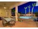 Covered patio featuring an outdoor dining area and a stunning view of the pool and palm trees at twilight at 4624 Leon De Oro Dr, Las Vegas, NV 89129