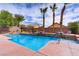 Sparkling pool with a cascading water feature surrounded by mature landscaping and palm trees at 4624 Leon De Oro Dr, Las Vegas, NV 89129