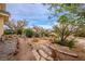 Backyard view with desert landscaping, various plants, rock features, stepping stones and trees beyond at 5081 Riata Pl, Pahrump, NV 89060