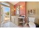 Bathroom featuring a sink with vanity, patterned wall, toilet, and an open door to the outside at 5081 Riata Pl, Pahrump, NV 89060