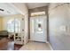 Entryway with white front door and damage in wall, tile flooring, and adjacent room at 5081 Riata Pl, Pahrump, NV 89060