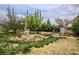Lush garden area featuring a windmill, assorted trees and bushes, and green grass at 5081 Riata Pl, Pahrump, NV 89060