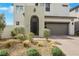 Close up of modern house with desert landscaping, gray garage door, and a unique front door at 513 Monarch Ridge Ct, North Las Vegas, NV 89084