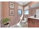 Well-lit powder room with wood vanity, toilet, modern fixtures, and two windows at 513 Monarch Ridge Ct, North Las Vegas, NV 89084