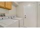 Bright laundry room features wood cabinets, white appliances, and a convenient side-access door at 5609 Red Bluff Dr, Las Vegas, NV 89130