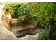 Backyard rock waterfall with lush greenery and flowering plants creating a peaceful outdoor space at 5609 Red Bluff Dr, Las Vegas, NV 89130