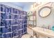 Bathroom features a Dallas Cowboys shower curtain, decorative shelving, and a vintage-style mirror at 5809 Robin Ln, Las Vegas, NV 89108