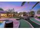 Expansive backyard boasts a pool, putting green, lounging areas, and charming string lights at 8275 W Craig Rd, Las Vegas, NV 89129