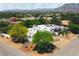 View of the surrounding neighborhood with a modern white home, lush landscaping, and the background view of mountains at 8525 W Verde Way, Las Vegas, NV 89149