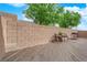 Spacious backyard area with a wooden deck, tall block wall, and green trees at 9024 Hazy Haven Ct, Las Vegas, NV 89149