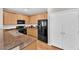 Kitchen featuring wood cabinets, dark appliances, granite countertops, and wood flooring that leads to the dining area at 9024 Hazy Haven Ct, Las Vegas, NV 89149