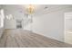 Open-concept living room with wood-look flooring and modern chandelier at 9491 Gainey Ranch Ave, Las Vegas, NV 89147