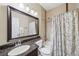 Well-lit bathroom with a granite countertop, patterned shower curtain, and decorative mirror at 10601 India Hawthorn Ave, Las Vegas, NV 89144