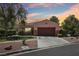 A front exterior shot of a one-story home with a well-manicured lawn and two-car garage at 10601 India Hawthorn Ave, Las Vegas, NV 89144