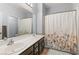 Bathroom featuring double sinks with a dark brown vanity and a shower with floral curtain at 11784 Golden Moments Ave, Las Vegas, NV 89138