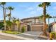 Elegant two-story home featuring a three-car garage and lush landscaping with mature palm trees at 11784 Golden Moments Ave, Las Vegas, NV 89138