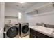 Updated laundry room with gray washer and dryer, a utility sink and storage shelf at 11784 Golden Moments Ave, Las Vegas, NV 89138