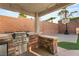 Outdoor kitchen with brick surround, grill, and mini-fridge, plus a basketball hoop in the yard at 11784 Golden Moments Ave, Las Vegas, NV 89138