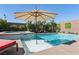 Stunning pool and spa surrounded by a lush lawn, mature landscaping, and a shade umbrella at 12053 Arrebol Ave, Las Vegas, NV 89138